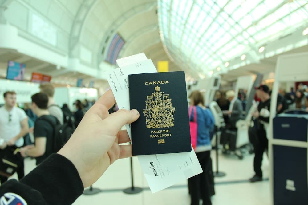 Hand holding a Canadian passport and boarding pass in an airport terminal